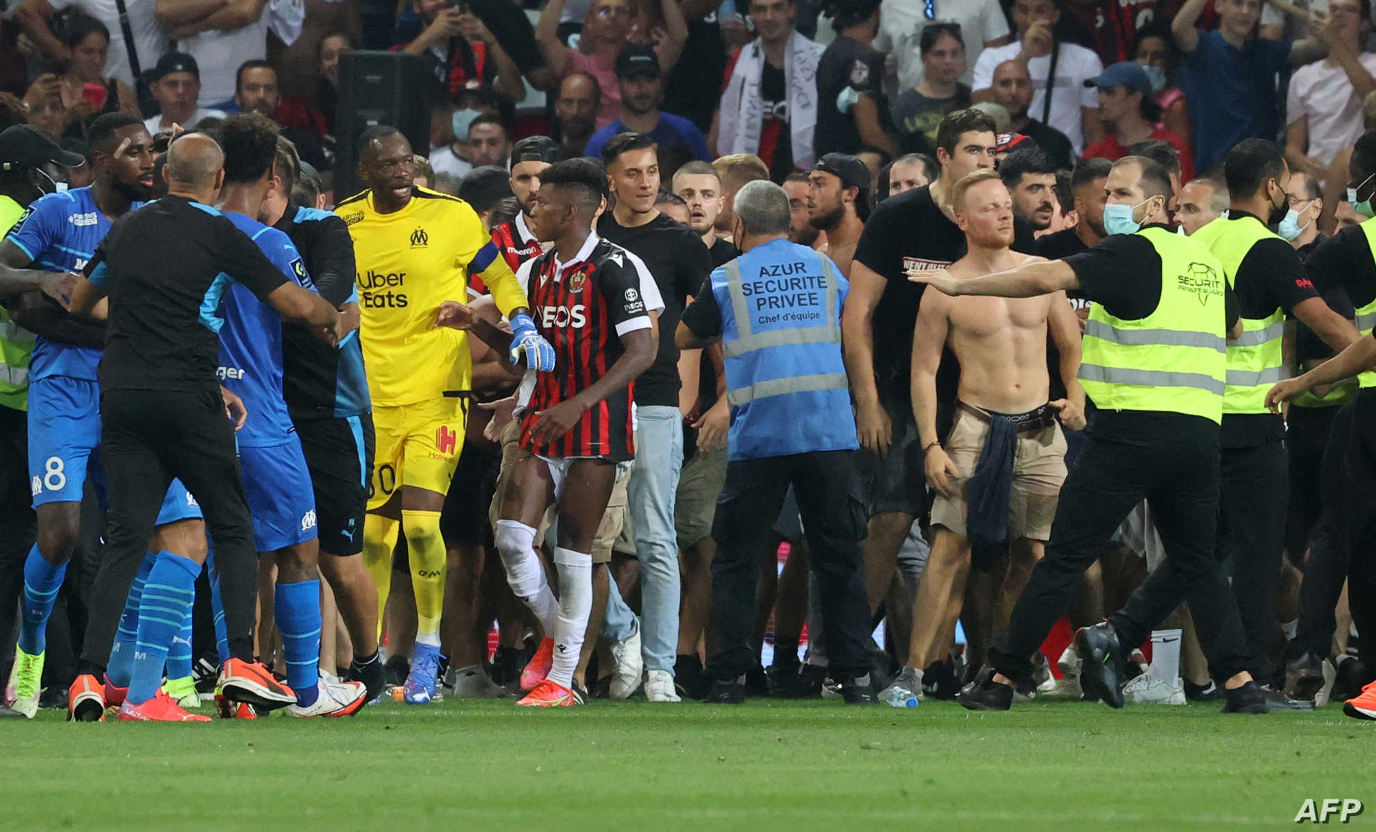 Fans try to invade the pitch during the French L1 football match between OGC Nice and Olympique de Marseille (OM) at the Allianz Riviera stadium in Nice, southern France on August 22, 2021. - The French Ligue 1 game between Nice and Marseille was halted on August 22, 2021, when fans of the home side invaded the pitch and angrily confronted opposing player Dimitri Payet. An AFP journalist at the game said trouble flared in the 75th minute when Marseille star Payet, who had been targeted by plastic bottles every time he took a corner, lobbed one back into the stands. (Photo by Valery HACHE / AFP)