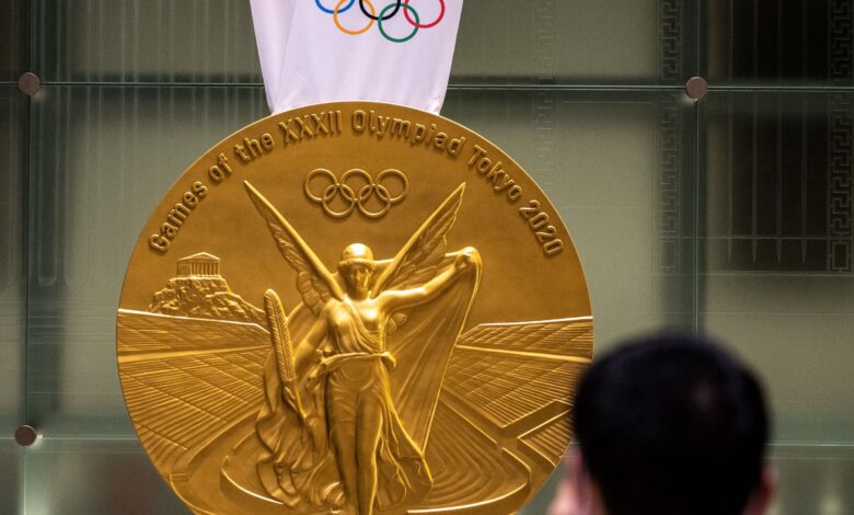 A man takes pictures of a large-scale reproduction of the Tokyo 2020 Olympic Games gold medal as part of the Olympic Agora event at Mitsui Tower in Tokyo on July 14, 2021. (Photo by Philip FONG / AFP) (Photo by PHILIP FONG/AFP via Getty Images)