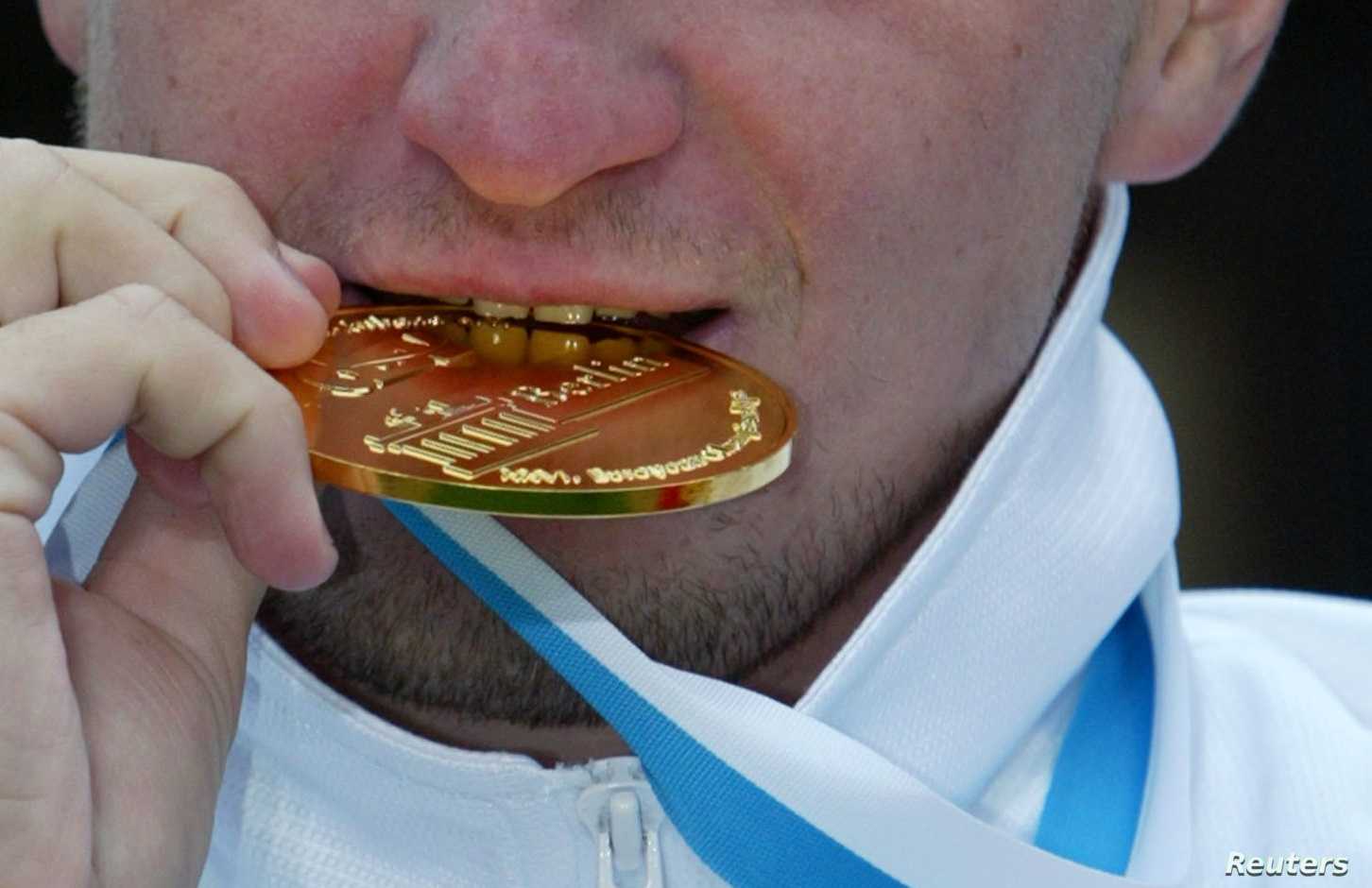 Russia's Yury Kudinov bites into his golden medal at the victory
ceremony after he won the men's 25 km Open Water race during the
European Swimming Championships in lake Templin in Potsdam, south of
the German capital Berlin on July 26, 2002. Russia's Yury Kudinov
clocked the fastest time in five hours nine minutes and 45 seconds
ahead of second placed Gilles Rondy of France and third placed David
Meca. REUTERS/Fabrizio Bensch
FAB/cmc