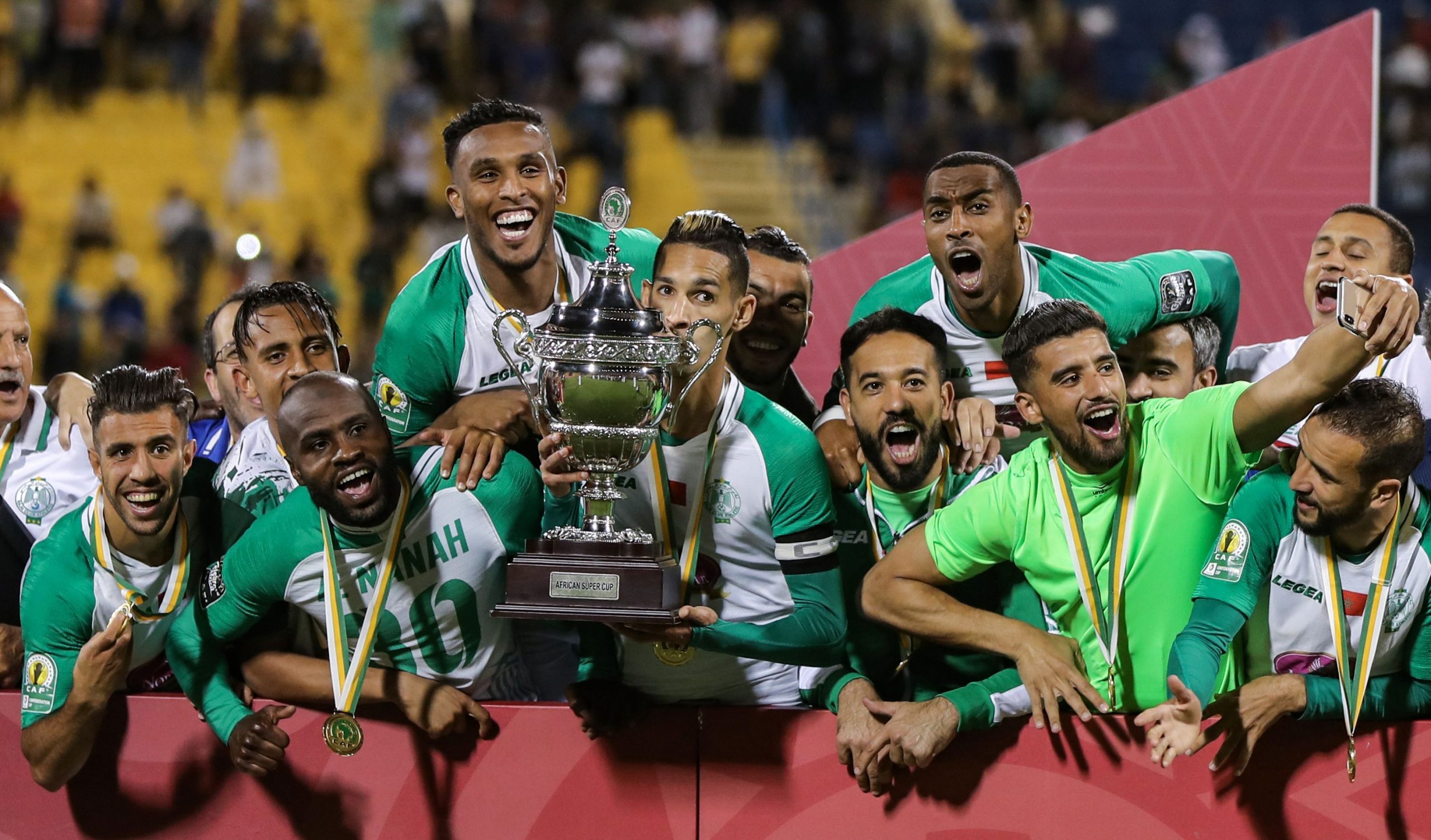 Raja Casablanca's players celebrate with the CAF Super Cup trophy after winning the match against ES Tunis at Thani bin Jassim Stadium in Al-Rayyan, Qatar, on March 29, 2019. (Photo by KARIM JAAFAR / AFP)