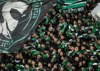 Supporters of Raja Club Athletic chant slogans and wave their flags as they attend a Moroccan Botola football match between Raja and Mouloudia Oujda in Casablanca on January 22, 2020. - From Casablanca to Algiers via Tunis, the chants belted out across football stadiums echo young North African fans' frustrations unrelated to the highs and lows of the beautiful game itself. Chants of "F'bladi delmouni!" ("Oppressed in my country!") at the demonstrations that have been commonplace in Algeria since last year originated on the noisy terraces manned by the ultras of Morocco's Raja Casablanca. (Photo by FADEL SENNA / AFP) (Photo by FADEL SENNA/AFP via Getty Images)