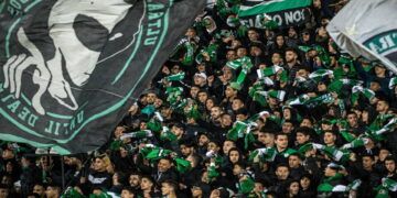 Supporters of Raja Club Athletic chant slogans and wave their flags as they attend a Moroccan Botola football match between Raja and Mouloudia Oujda in Casablanca on January 22, 2020. - From Casablanca to Algiers via Tunis, the chants belted out across football stadiums echo young North African fans' frustrations unrelated to the highs and lows of the beautiful game itself. Chants of "F'bladi delmouni!" ("Oppressed in my country!") at the demonstrations that have been commonplace in Algeria since last year originated on the noisy terraces manned by the ultras of Morocco's Raja Casablanca. (Photo by FADEL SENNA / AFP) (Photo by FADEL SENNA/AFP via Getty Images)