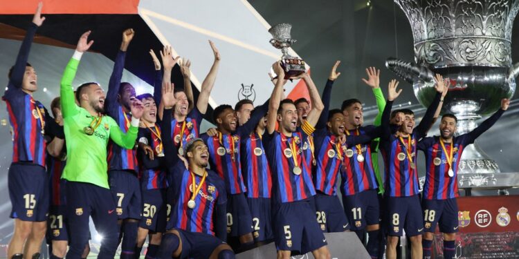 Barcelona's players celebrate on the podium after winning the Spanish Super Cup final football match between Real Madrid CF and FC Barcelona at the King Fahd International Stadium in Riyadh, Saudi Arabia, on January 15, 2023. (Photo by Giuseppe CACACE / AFP)