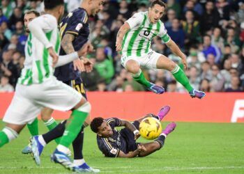 Real Betis' Mexican midfielder #18 Andres Guardado jumps over Real Madrid's Brazilian forward #11 Rodrygo during the Spanish league football match between Real Betis and Real Madrid CF at the Benito Villamarin stadium in Seville on December 9, 2023. (Photo by CRISTINA QUICLER / AFP)