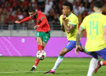 Morocco's defender Noussair Mazraoui (L) attempts a shot during a friendly football match between Morocco and Brazil at the Ibn Batouta Stadium in Tangier on March 26, 2023. (Photo by Fadel Senna / AFP)