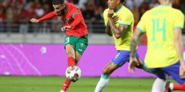 Morocco's defender Noussair Mazraoui (L) attempts a shot during a friendly football match between Morocco and Brazil at the Ibn Batouta Stadium in Tangier on March 26, 2023. (Photo by Fadel Senna / AFP)